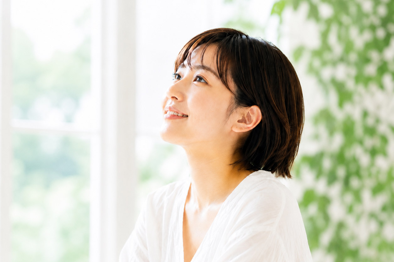 明るい窓辺でリラックスして上を見上げる女性